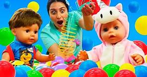 Giocattoli per i bambini piccoli tra le palline colorate. Giochi divertenti con le bambole per bimbi