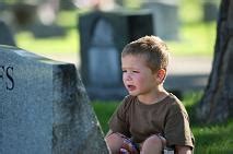 Child asking for forgiveness in front of a tombstone